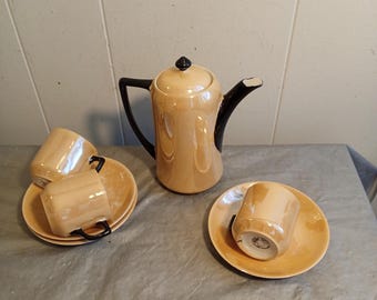 Puede incluir: Un juego de té vintage de color melocotón, que incluye una tetera con asa y boquilla negras, y tazas y platillos a juego. El juego incluye tres tazas y platillos. La tetera tiene tapa y asa negras.