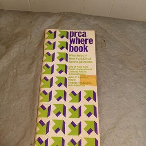 Op de afbeelding: Een vintage "prca where book" gids voor New York City. De omslag heeft een herhalend patroon van groene en paarse pijlen op een crèmekleurige achtergrond. Tekst bevat "What to do in New York City & how to get there."