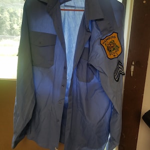 May include: A light blue long-sleeved shirt with a patch on the left sleeve that reads "Hamburg Police N.J."