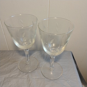 May include: Two clear glass wine glasses with etched floral designs.