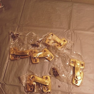 May include: A package of six gold-toned door latches with screws. The latches are in individual plastic bags.