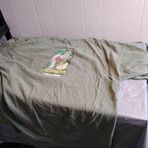 Puede incluir: Camiseta verde con un logotipo vintage de 7 Up que presenta un lim&oacute;n y el texto "7 Up, Now with a Twist!" y "The Only Drink Refreshingly You!"