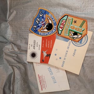 Può includere: Memorabilia di bowling vintage con due toppe ricamate con il testo "ABC Triplicate Award" e grafiche di birilli. Sono inclusi anche certificati di premiazione e una busta "First Class", tutti dell'American Bowling Congress.
