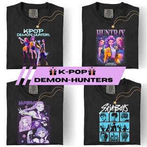 May include: Four black t-shirts with different graphic designs. One shirt features the text "KPOP DEMON HUNTERS" with a group of animated figures. Another displays "HUNTRIX" with a group of animated women. The third shirt shows "HUNTRIX" with an animated woman. The last shirt has "SAJA BOYS" with animated figures.