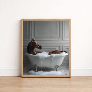 May include: A framed print showing a brown horse in a white clawfoot bathtub filled with bubbles. The horse is reclining, with its head and upper body visible. The background features a grey wall with decorative paneling.