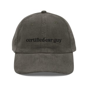 May include: Olive green corduroy baseball cap with the text "certified car guy" embroidered in black. The cap has a curved brim and an adjustable strap at the back. A classic, casual accessory.