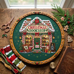 May include: A circular wooden embroidery hoop containing a cross-stitch design of a Christmas bookshop on dark green fabric. The shop features a snowy roof, a sign reading CHRISTMAS BOOKSHOP, a decorated door, and presents. Includes embroidery floss.