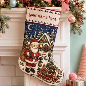 Peut inclure: Une chaussette de Noël avec un motif en point de croix représentant le Père Noël portant un sac, une maison enneigée, une lanterne et un traîneau rempli de cadeaux sous un ciel étoilé. Le revers porte le texte your name here en rouge.