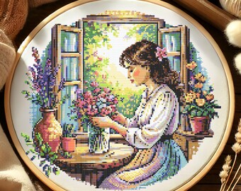 May include: A cross-stitch embroidery of a woman arranging flowers in a vase by a window. The woman is wearing a white blouse and a blue and purple skirt. The flowers are pink, purple, and yellow. The window is open and there are green plants outside.