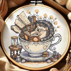 Puede incluir: Bordado de punto de cruz en un aro de madera que representa un erizo con gafas y un sombrero, leyendo libros dentro de una taza de té. La taza de té está sobre un platillo con más libros. Un reloj de arena y una mesita están a la izquierda.