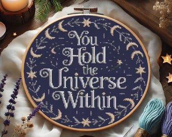 May include: A blue and white embroidery hoop with the text "You Hold the Universe Within" surrounded by stars and crescent moons.