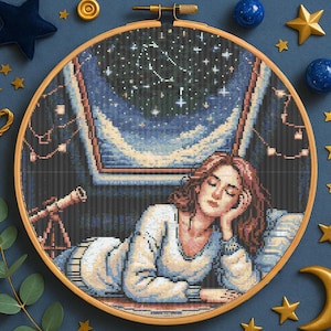 Puede incluir: Un bordado de punto de cruz en un aro de madera representa a una mujer mirando un cielo estrellado a través de una ventana. La mujer lleva una blusa blanca y apoya la cabeza en la mano. Se ve un telescopio.