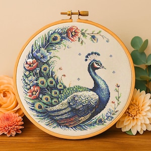 May include: A cross-stitch embroidery hoop with a peacock design. The peacock is blue and green with a long tail of feathers. The background is white with small flowers.
