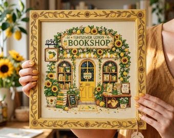 May include: A framed cross-stitch embroidery depicting a storefront titled SUNFLOWER LEMON BOOKSHOP. The design features a yellow door, bookshelves, and climbing sunflowers and lemons. The wooden frame is decorated with a repeating lemon and sunflower pattern.