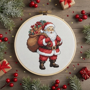 Peut inclure: Une broderie au point de croix du Père Noël portant un grand sac de cadeaux. Le Père Noël est vêtu d'un costume rouge avec des bordures blanches, une ceinture noire et des bottes. La broderie est dans un cercle en bois, avec des décorations de Noël.