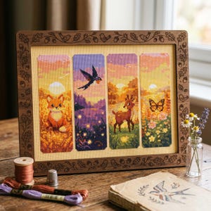 May include: A framed cross-stitch artwork with four vertical panels showing nature scenes. The panels depict a fox, a bird, a deer, and a butterfly, set against a sunset. The wooden frame is decorated with carved birds, acorns, and leaves.