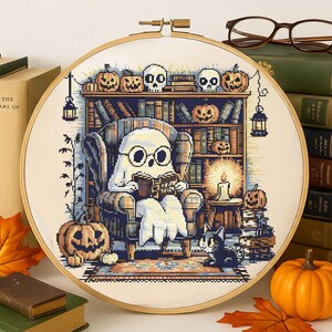 Ghost Reading in Haunted Library Cross-Stitch Pattern – Cozy Ghost with Glasses in Armchair Surrounded by Books, Pumpkins, Skulls and Candles for Halloween Decor
This charming Halloween cross-stitch design features a sweet ghost nestled in an armchair reading Ghost Tales. The cozy haunted library setting is rich with spooky details – pumpkins grin from bookshelves, skulls rest on top of ancient tomes, and glowing candles light the room. A curious cat peers up from below