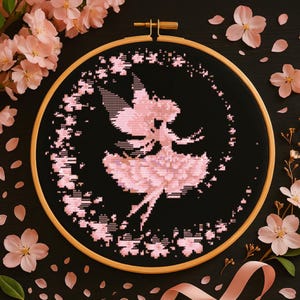 Könnte beinhalten: Eine rosa Feensilhouette, die auf schwarzem Stoff gestickt ist, umgeben von einem Kreis aus rosa Blüten. Die Stickerei befindet sich in einem Reifen.