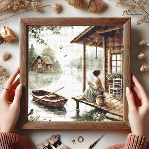 May include: A painting of a woman sitting on a porch overlooking a lake with a small cabin in the background. The woman is wearing a blue dress and has her hair pulled back. There are two boats in the water and a wooden railing in front of the porch.