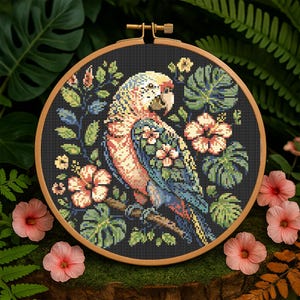 May include: A cross-stitch embroidery hoop with a colorful parrot perched on a branch surrounded by tropical flowers and leaves on a black background.