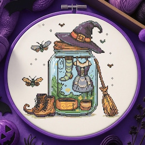 Può includere: Ricamo a punto croce in un cerchio viola. Il disegno presenta un cappello da strega, un vestito, stivali e una scopa all'interno di un barattolo. Falene e piccole stelle sono sparse intorno al barattolo. Lo sfondo è viola chiaro.