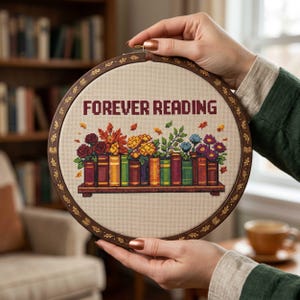 May include: A cross-stitch embroidery hoop with the words "FOREVER READING" in burgundy. The design features a shelf of colorful books with flowers and leaves. The wooden hoop is approximately 8 inches in diameter.