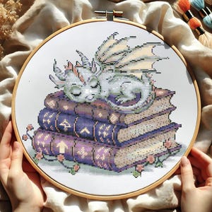 Patrón de punto de cruz de dragón dormido sobre libros, bordado de fantasía acogedor, punto de cruz de criatura mítica, punto de cruz de biblioteca encantada
