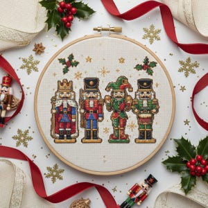May include: A cross-stitch embroidery hoop featuring four toy soldier nutcrackers in a row. The nutcrackers are in various colors, including red, green, and blue. The background is white, with red ribbon, holly, and gold snowflakes.