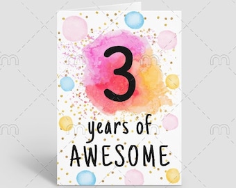 May include: A white card with a pink, orange, and yellow watercolor background. The number "3" is in black text on the watercolor background. The text "years of AWESOME" is in black text below the number. The card is decorated with gold glitter and colorful polka dots.