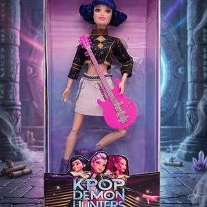 May include: A doll in a box. The doll has blue hair, a black and gold top, and a white skirt, holding a pink guitar. The box is labelled "KPOP DEMON HUNTERS" and "3+". The background depicts a fantasy scene with pillars and purple accents.