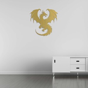 Pu&ograve; includere: Decorazione murale dorata raffigurante un drago con ali spiegate e squame dettagliate. Il drago &egrave; fissato a una parete bianca sopra un mobile bianco. La stanza ha un pavimento in legno.