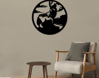 Op de afbeelding: Zwarte metalen wandkunst met een wolf die huilt naar de maan. De wolf is gesilhouetteerd tegen een volle maan en wolken. De kunst is rond en hangt aan een beige muur boven een houten stoel en tafel.