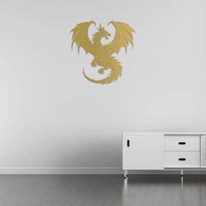 Pu&ograve; includere: Decorazione murale dorata raffigurante un drago con ali spiegate e squame dettagliate. Il drago &egrave; fissato a una parete bianca sopra un mobile bianco. La stanza ha un pavimento in legno.