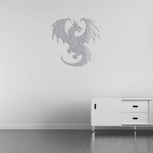 Pu&ograve; includere: Decorazione murale a forma di drago argentato con ali spiegate, coda arricciata e squame dettagliate. Il drago &egrave; montato su una parete bianca sopra un mobile bianco con cassetti. Pavimento in legno.
