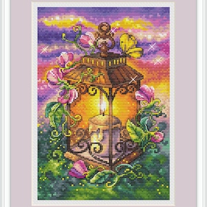 Könnte beinhalten: Kreuzstich-Kunstwerk einer Laterne mit einer brennenden Kerze, umgeben von rosa Blumen und grünen Ranken. Der Hintergrund zeigt einen Sonnenuntergang in Lila, Orange und Gelb. Ein gelber Schmetterling sitzt auf der Laterne.