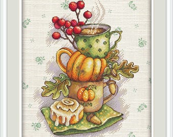 May include: A cross-stitch design featuring a stack of fall-themed mugs and a cinnamon roll. The top mug is green with white polka dots and steam rising from it. A pumpkin-shaped mug sits below, and a mug with a pumpkin graphic is at the bottom.