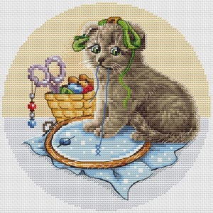 May include: A cross-stitch design of a grey kitten with green eyes, playing with embroidery threads. A basket of yarn, scissors, and an embroidery hoop are also visible. The kitten is surrounded by craft supplies.