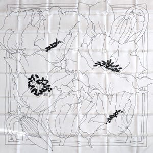 May include: A white square scarf with a black floral design. The scarf features large, stylized poppy flowers outlined in black, with black seed pods in the center. The design is set against a white background, creating a high-contrast, elegant look.