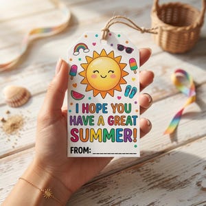May include: A white gift tag with a summer theme, held by a hand. The tag features a smiling sun, rainbow, sunglasses, watermelon, and text that reads "I HOPE YOU HAVE A GREAT SUMMER!" with space to write "FROM:"