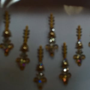 May include: A set of seven gold-toned, decorative, jeweled body stickers. The stickers are designed to be applied to the forehead, face, or body.