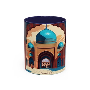 Puede incluir: Taza de cerámica con una ilustración detallada de una mezquita con una gran cúpula azul y minaretes. La obra de arte está ambientada en un cielo cálido color puesta de sol. La palabra "BUKHARA" está impresa en la parte inferior.