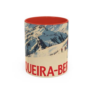 Może przedstawiać: Ceramiczny kubek z czerwonym wnętrzem i kremowym nadrukiem. Kubek przedstawia ilustrację w stylu vintage ośnieżonego pasma górskiego z narciarzami i czerwonym napisem "QUEIRA-BER".