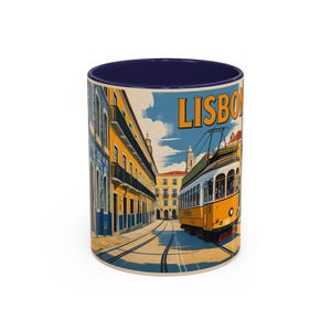 May include: A ceramic coffee mug with a blue interior and a wraparound illustration of a Lisbon street scene. The design features a yellow tram, buildings, and the word "LISBON" in orange.