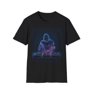 Puede incluir: Camiseta negra con un gráfico de neón de un DJ encapuchado en una mesa de mezclas. La imagen está creada con líneas azules y rosas. La camiseta es de cuello redondo.