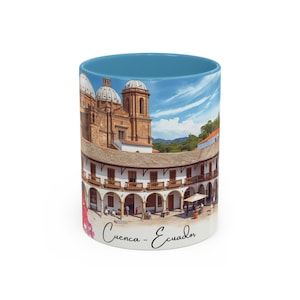 May include: A white ceramic mug with a blue interior features a detailed image of a historic building in Cuenca, Ecuador. The image includes a church with domes and a colonnaded structure. The text "Cuenca - Ecuador" is written in cursive on the mug.