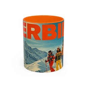 Pode incluir: Caneca de cerâmica com interior laranja, exibindo a palavra "VERBIER" em laranja. O design apresenta uma ilustração vintage de esquiadores em uma montanha nevada, contra um céu azul. Ideal para bebidas quentes.