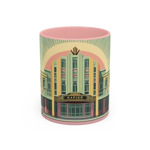 Puede incluir: Taza de cerámica con un diseño Art Déco de un edificio, con la palabra "NAPIER" en dorado. La taza tiene un interior rosa y un exterior verde claro, amarillo y rosa. El diseño recuerda a los años 30.