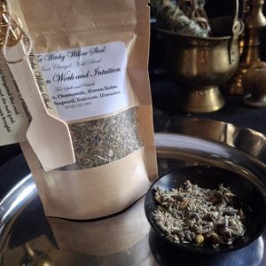 May include: A brown paper pouch labeled Witchy Willow Shed Moon Charged Herb Blend for Dream Work and Intuition, containing dried herbs including chamomile, lemon balm, mugwort, valerian, and damiana. A small wooden scoop is attached to the front.