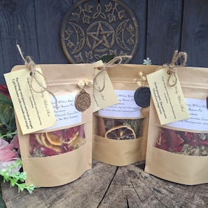 May include: Three light brown paper pouches containing dried botanical ingredients for simmering. Each pouch features a clear window, a tied jute string with a paper tag, and a decorative wax seal. The contents include dried citrus slices, petals, and herbs.