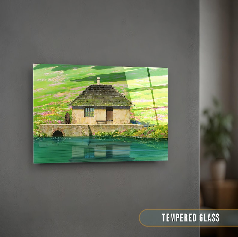May include: A painting of a small, stone house with a green roof, set against a backdrop of rolling green hills and a blue lake. The house has a single window and a wooden door. The painting is framed in a simple, black frame.